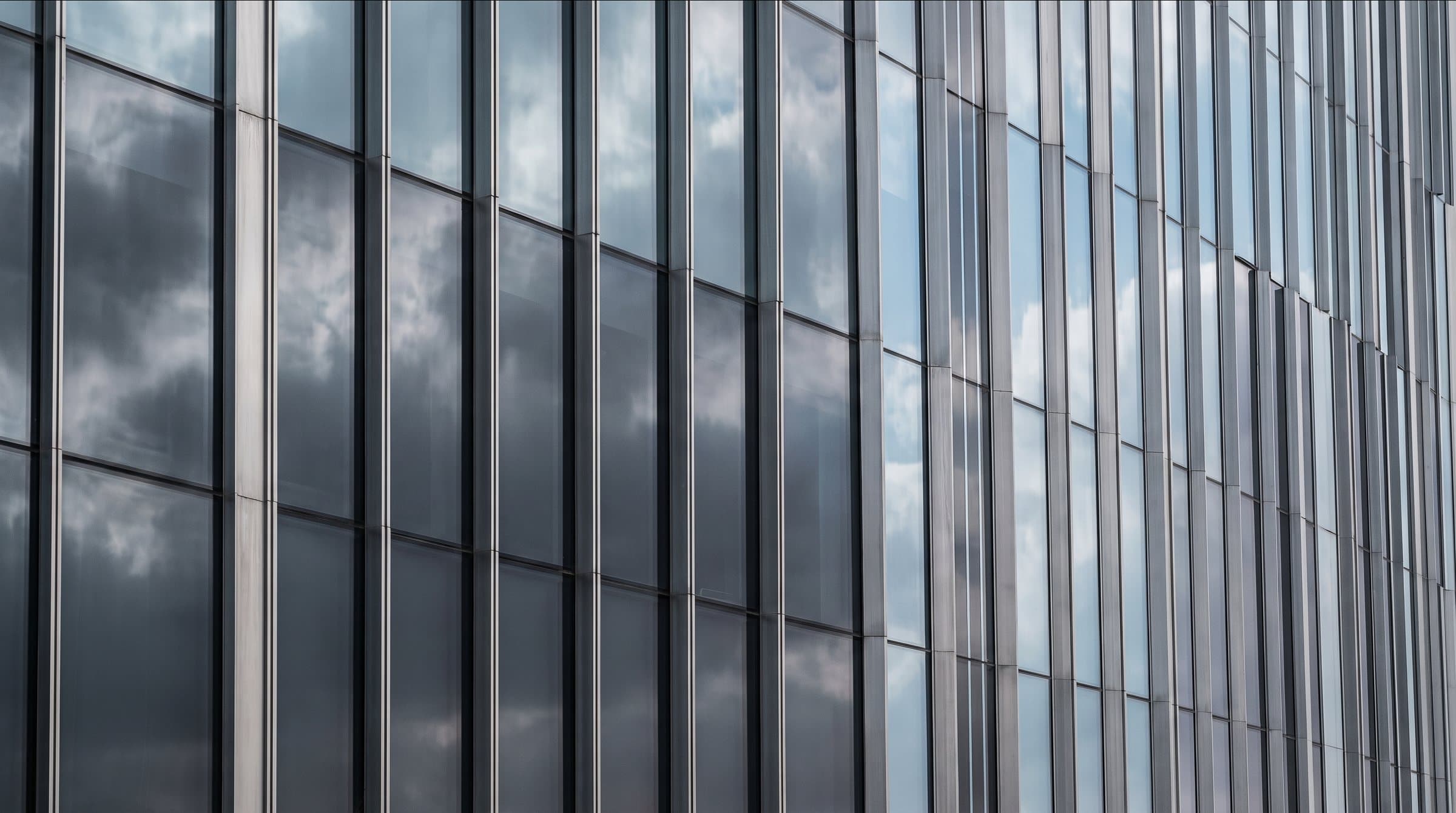 Close view of a glass façade reflecting clouds