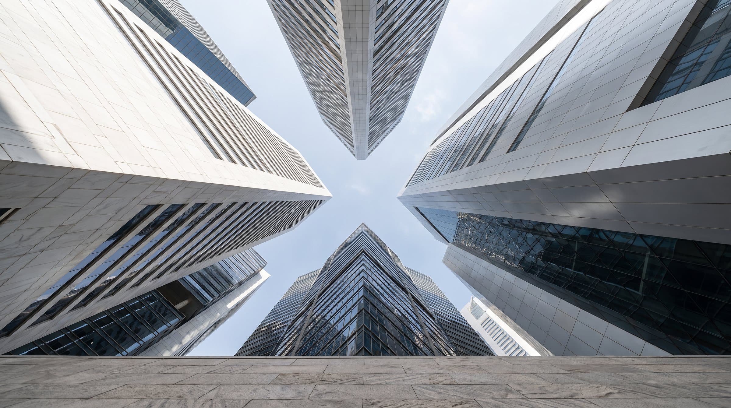 Glass and stone towers meeting overhead against a pale sky